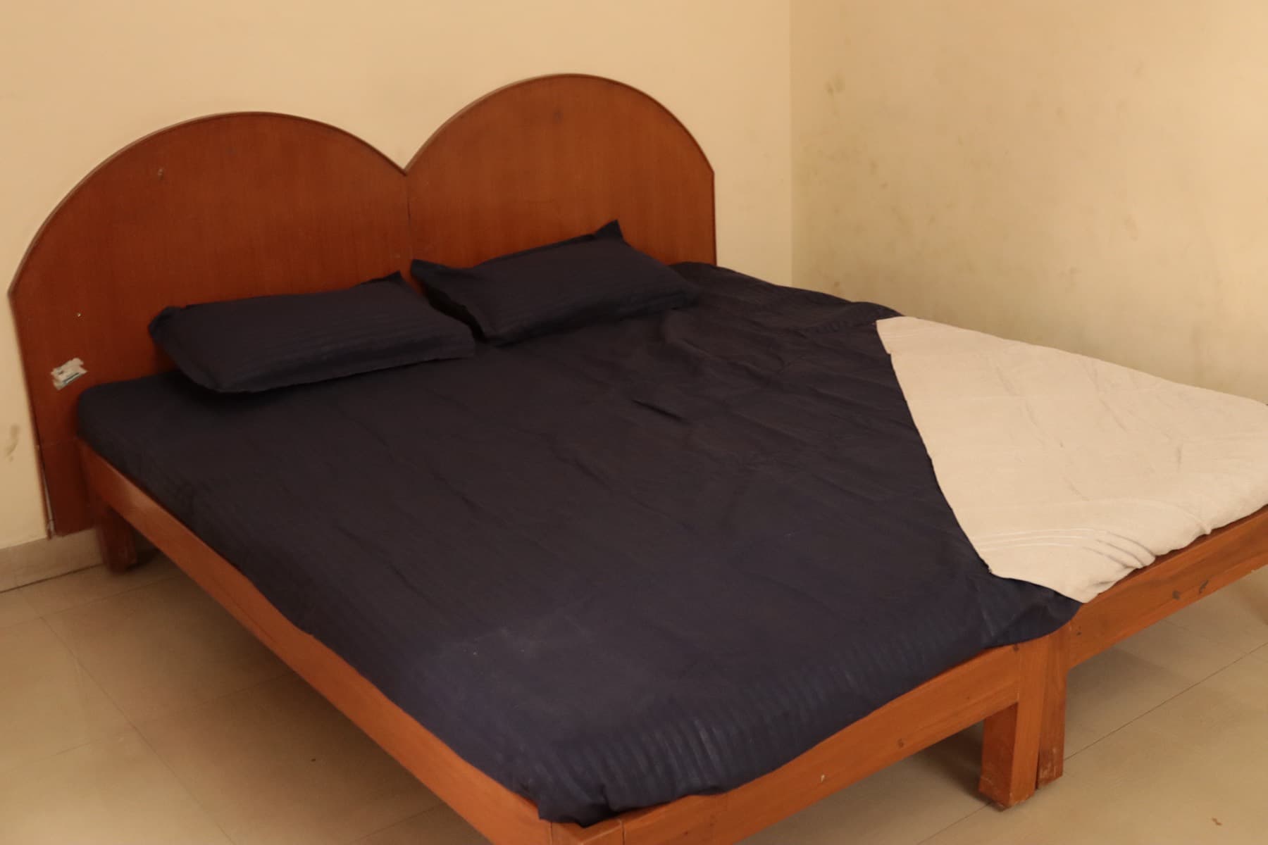 Double bed with wooden headboard in the Deluxe AC Double Room